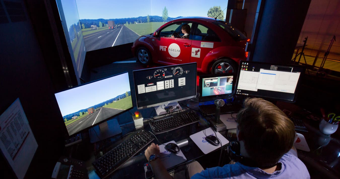 Man sitting at a computer monitoring the driving controls