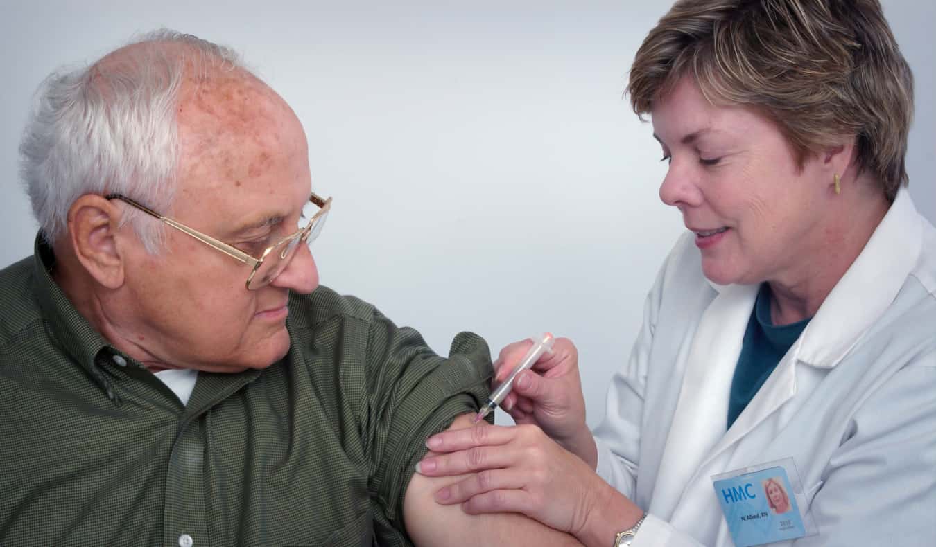 Elderly man getting a vaccine shot by a nurse 